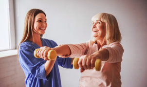 caregiver assisting senior woman in her exercise