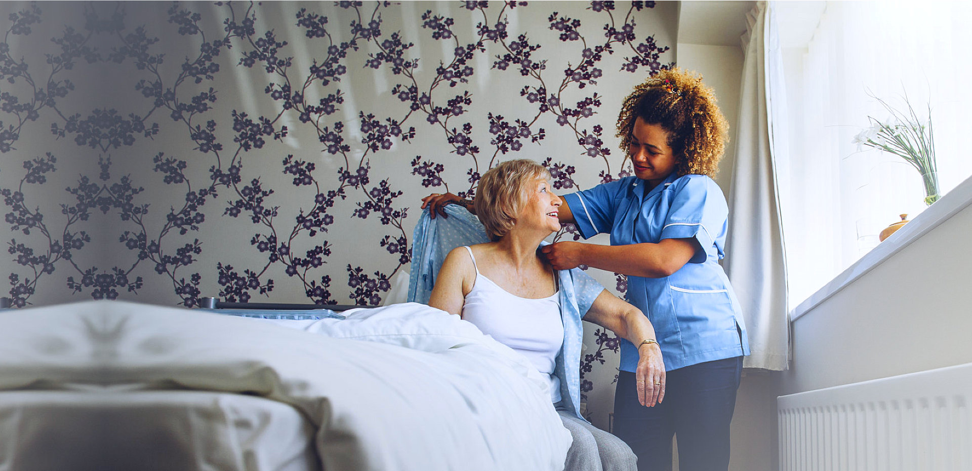 caregiver assisting senior woman in getting dressed