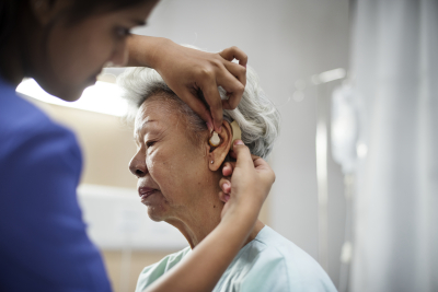 caregiver assisting senior woman for her hearing aid