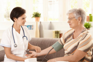 nurse checking blood pressure of senior woman