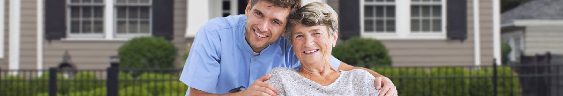 male caregiver with senior woman on wheelchair smiling